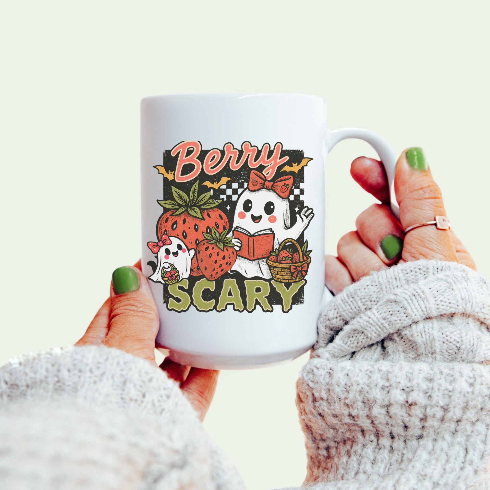Mug with ghost and strawberry design reading 'Berry Scary' held by a person.