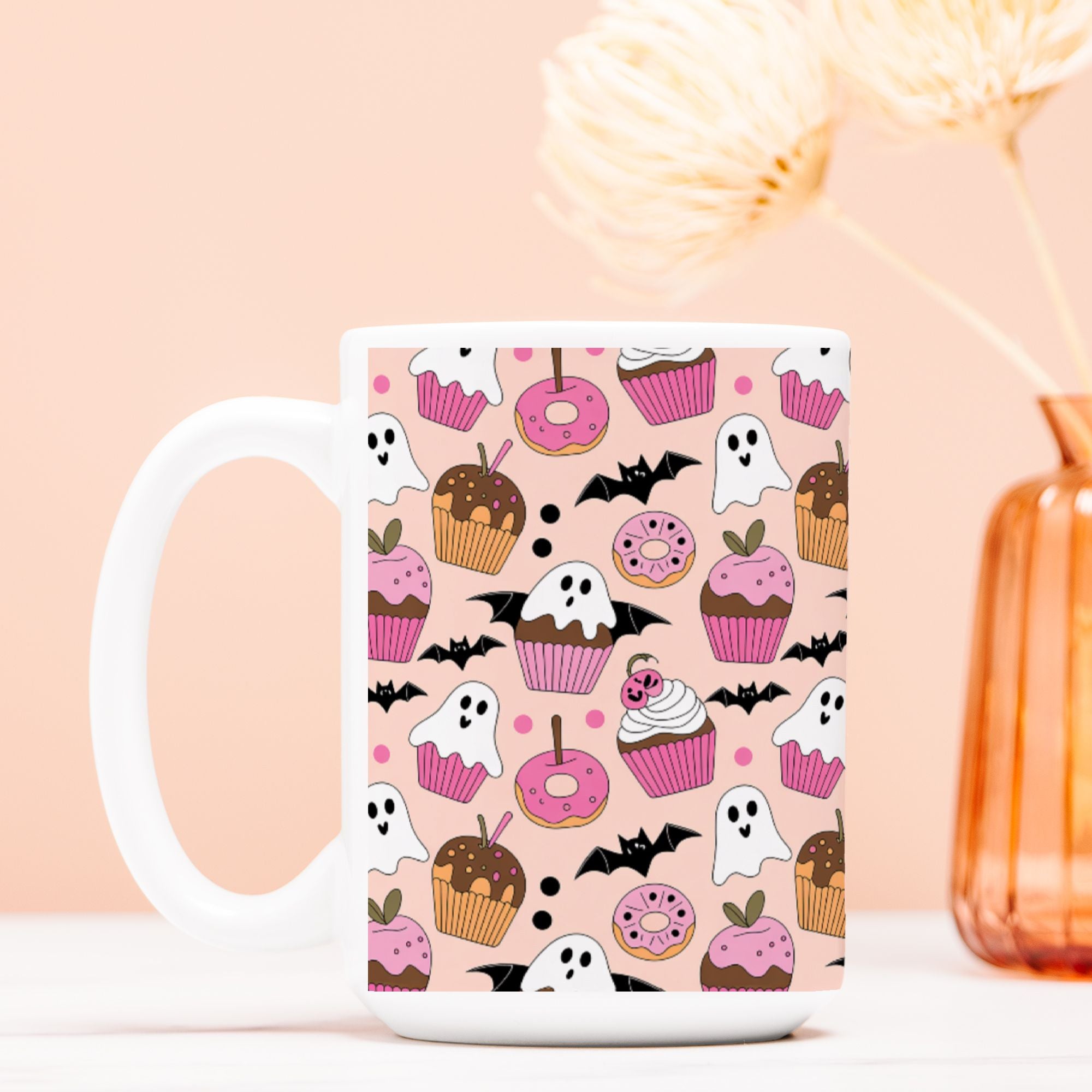 Mug with Halloween-themed design featuring ghosts, cupcakes, and donuts on a pink background.