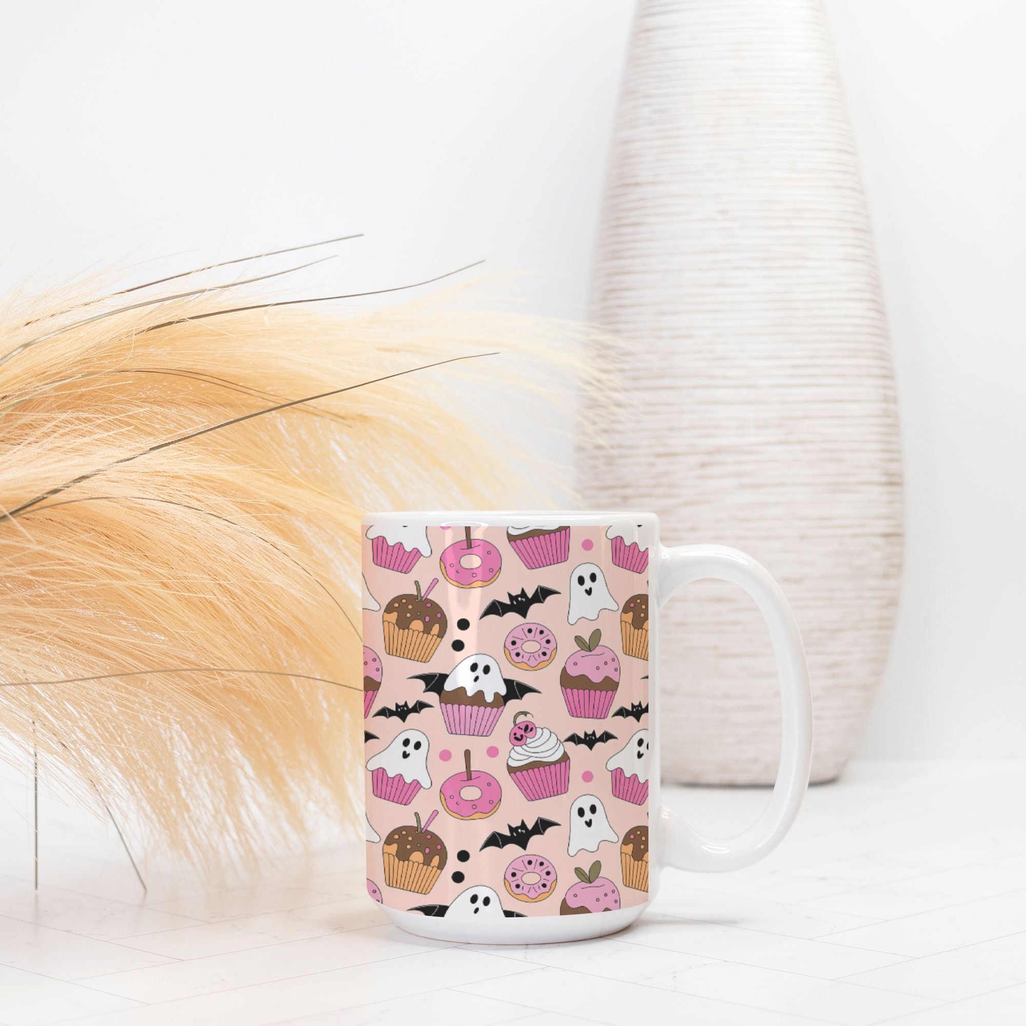 White mug with Halloween-themed pink pattern on a white surface with decorative elements.