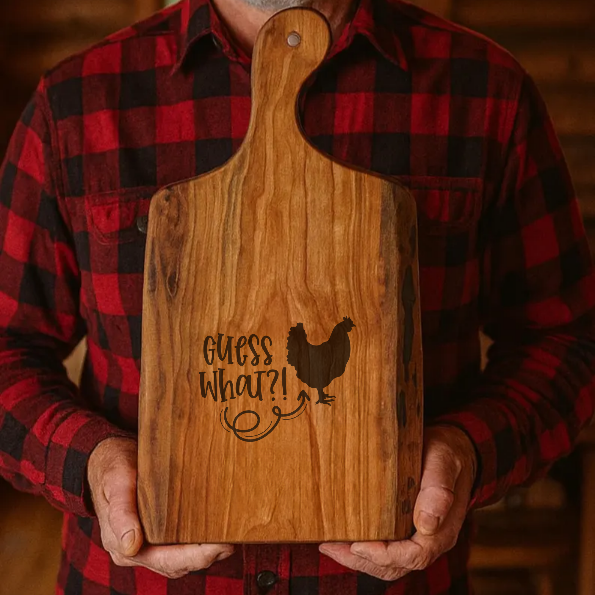 Person holding a wooden cutting board with 'Guess What?!' and a chicken silhouette.