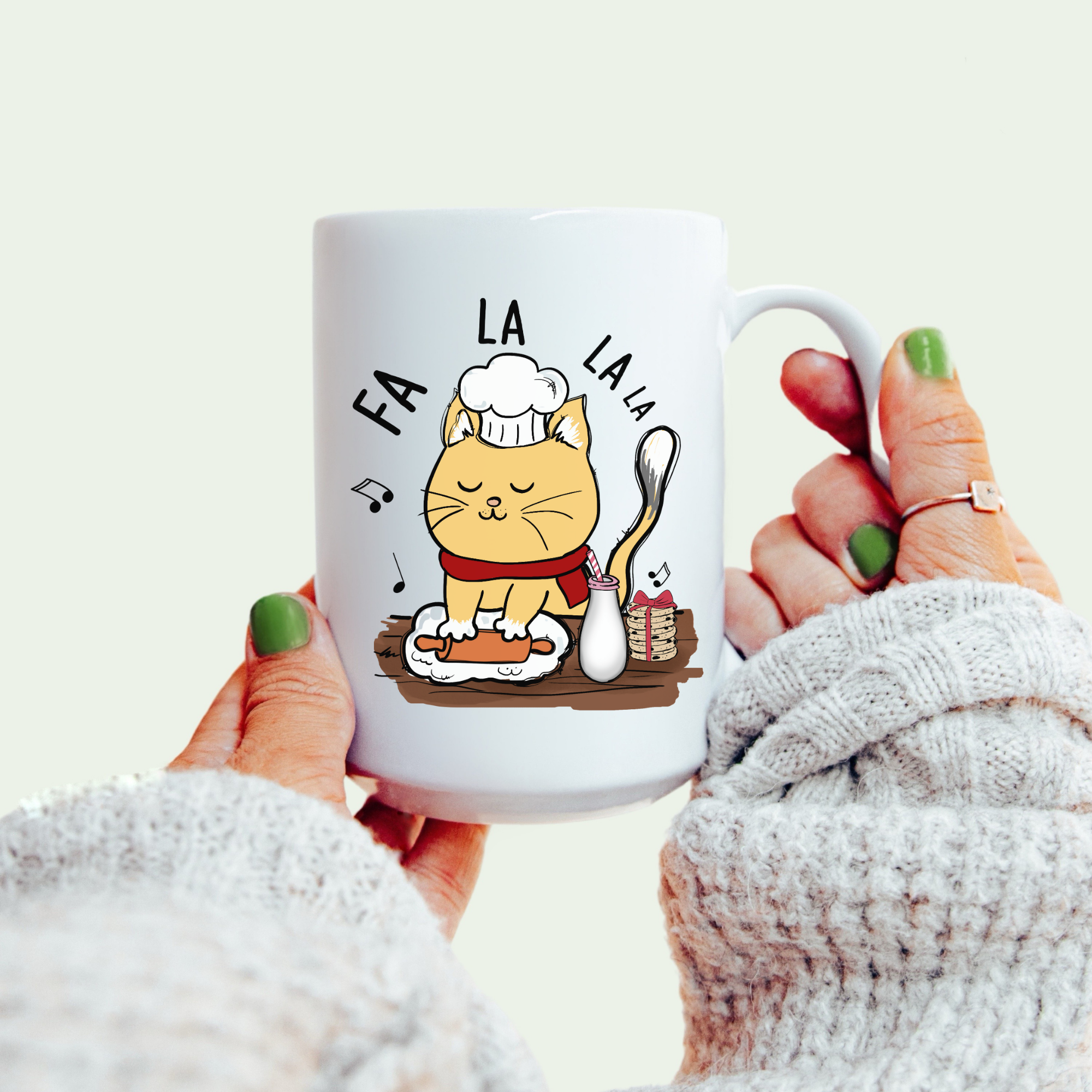 White mug with a cat illustration and 'FA LA LA LA' text, held by a person.