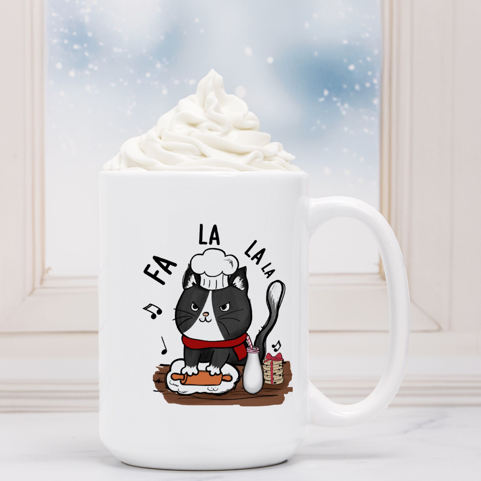 White mug with a cat design and 'Fa La La La' text, filled with hot chocolate.