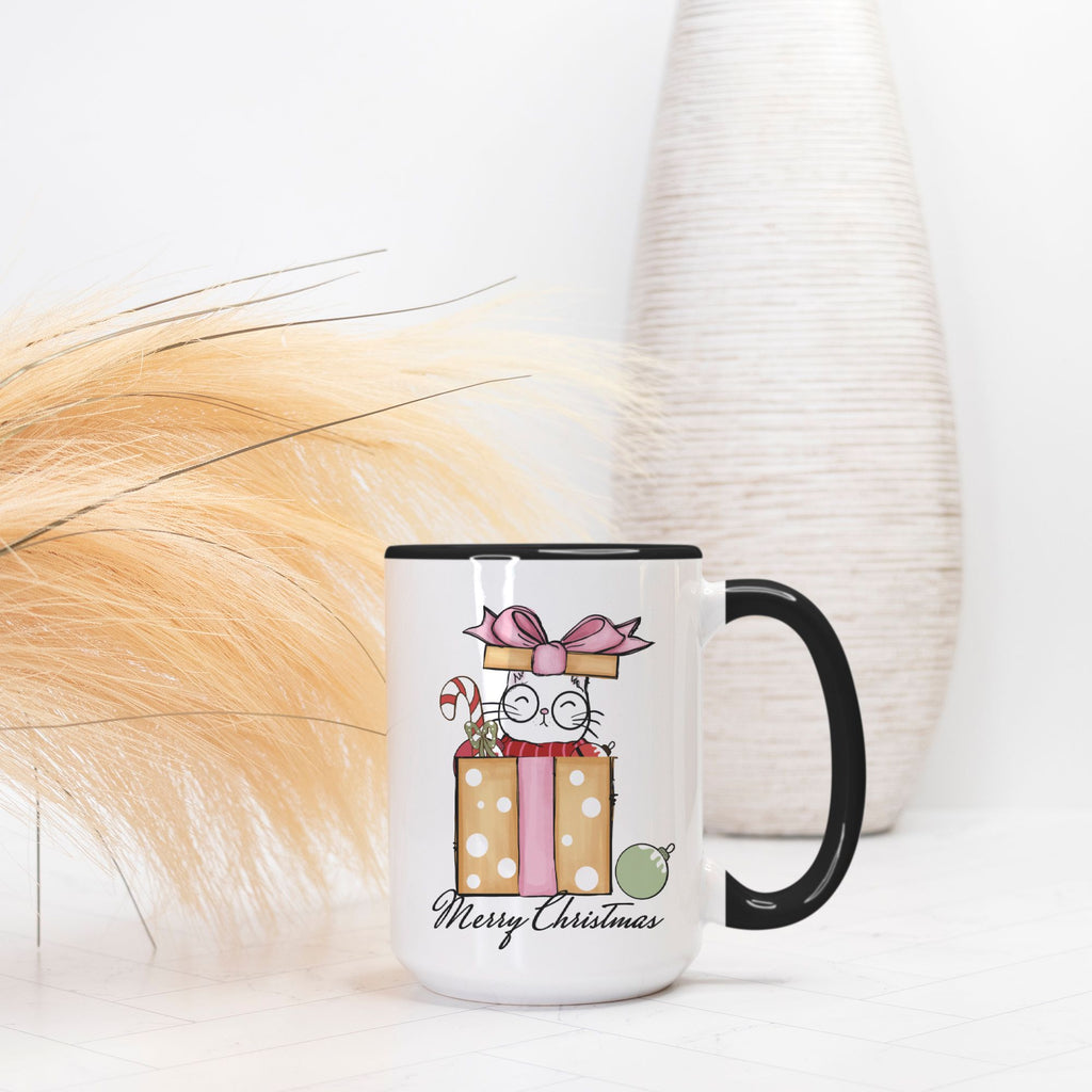 Mug with Christmas design featuring a cat and presents on a white surface.