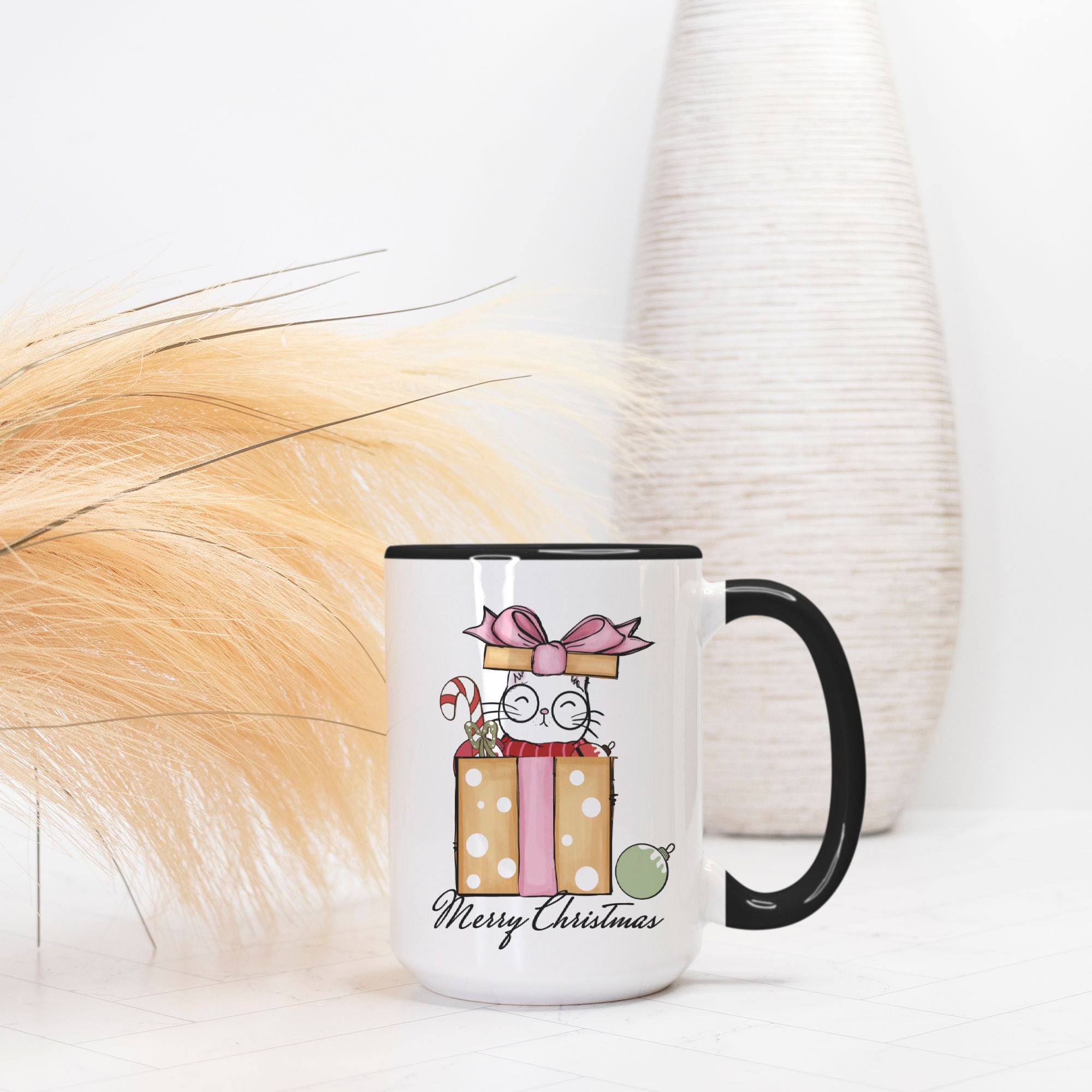 Mug with Christmas design featuring a cat and presents on a white surface.