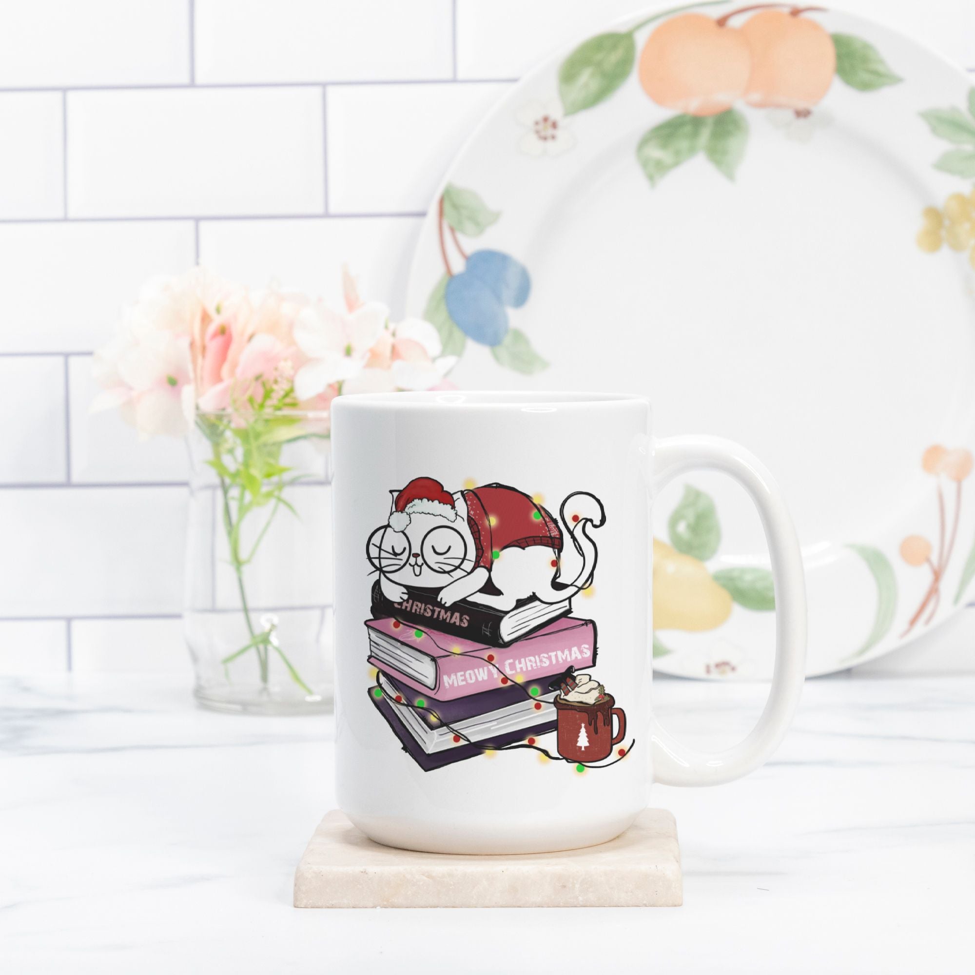 White mug with a Christmas-themed design featuring a cat, books, and a mug on a white surface.