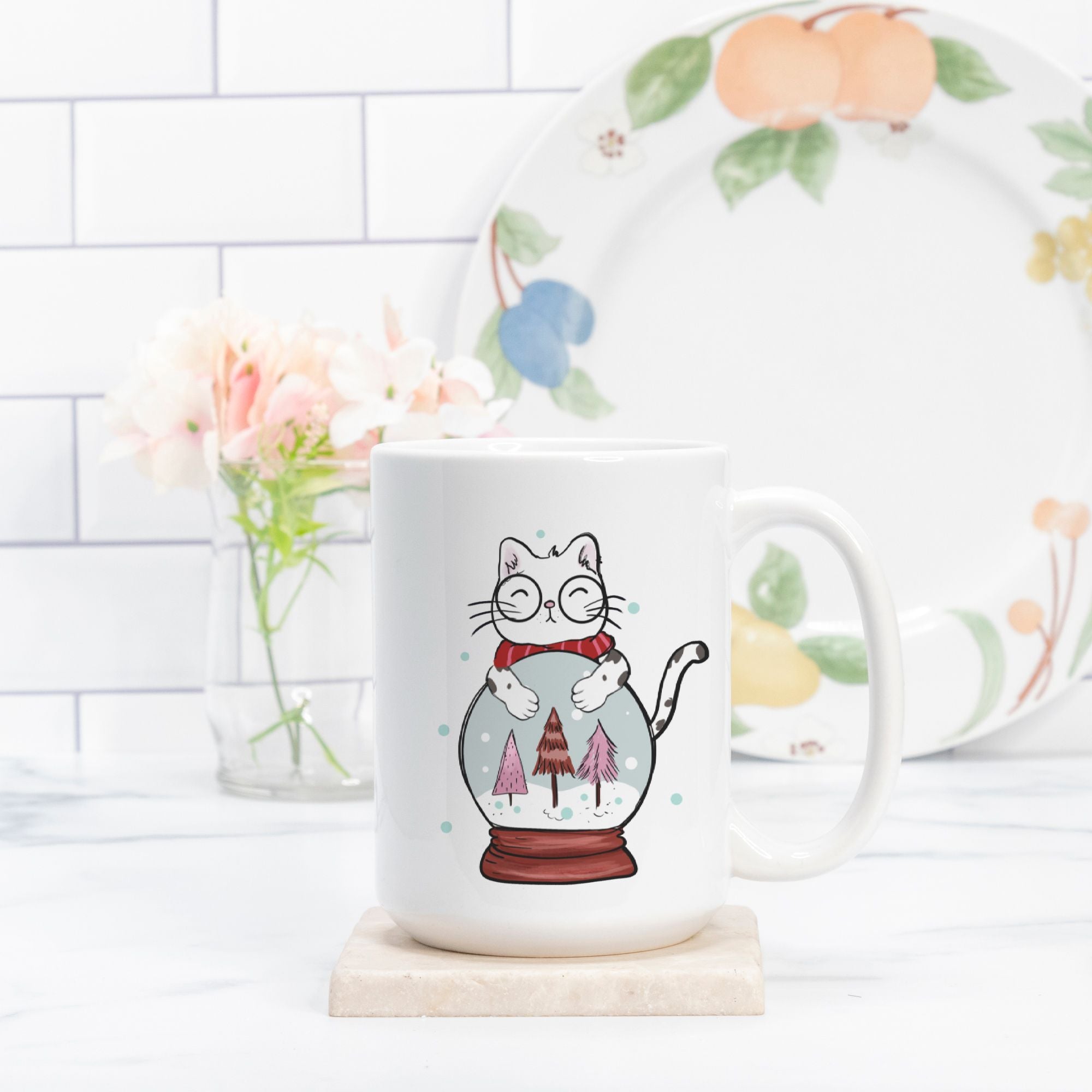 Mug with a cat design holding a snow globe on a kitchen counter.