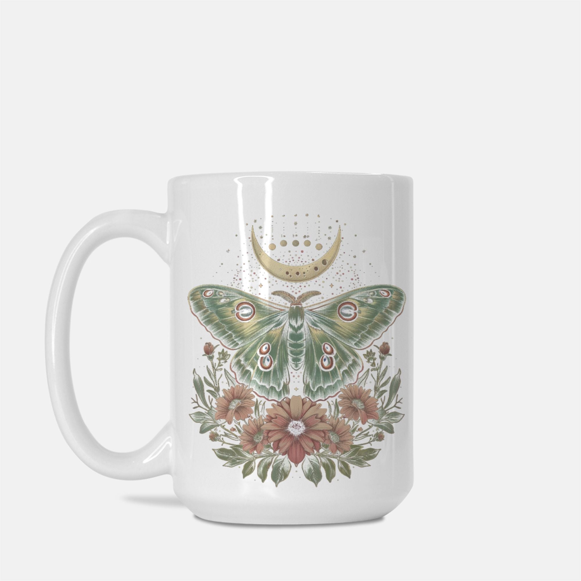 White mug in studio with and intricate design of a cottage core Luna moth with flowers and a partial celestial moon in colors of green, gold, and pink.