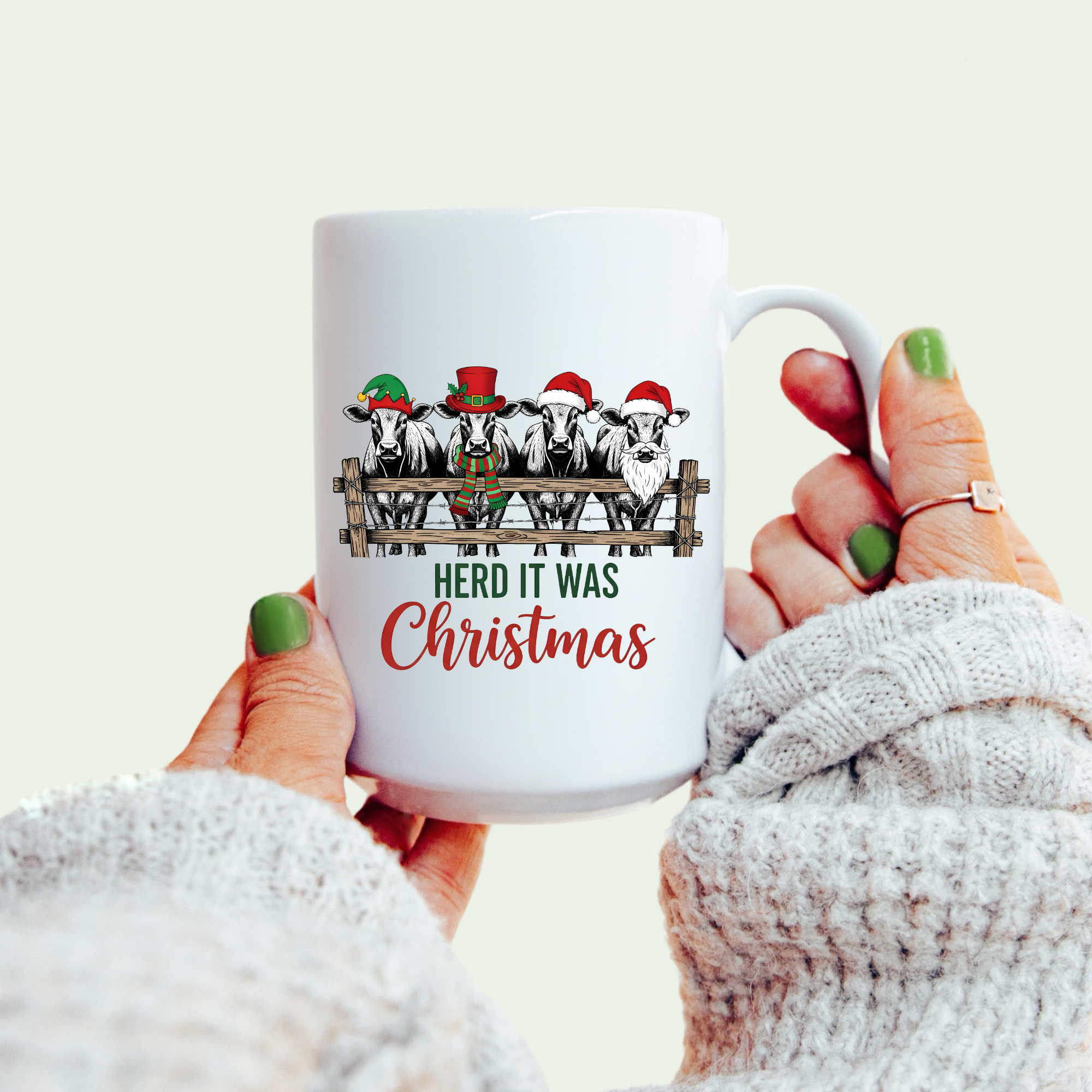 Mug with Christmas design of cows wearing hats and text 'Herd it was Christmas' held by a person.