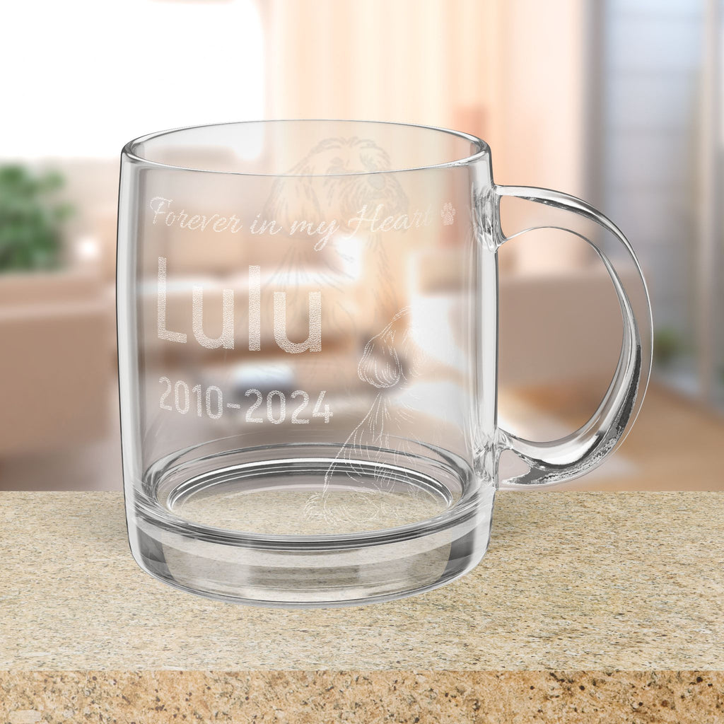 Clear glass mug with engraved memorial text and Bichon Frise dog illustration on a blurred background