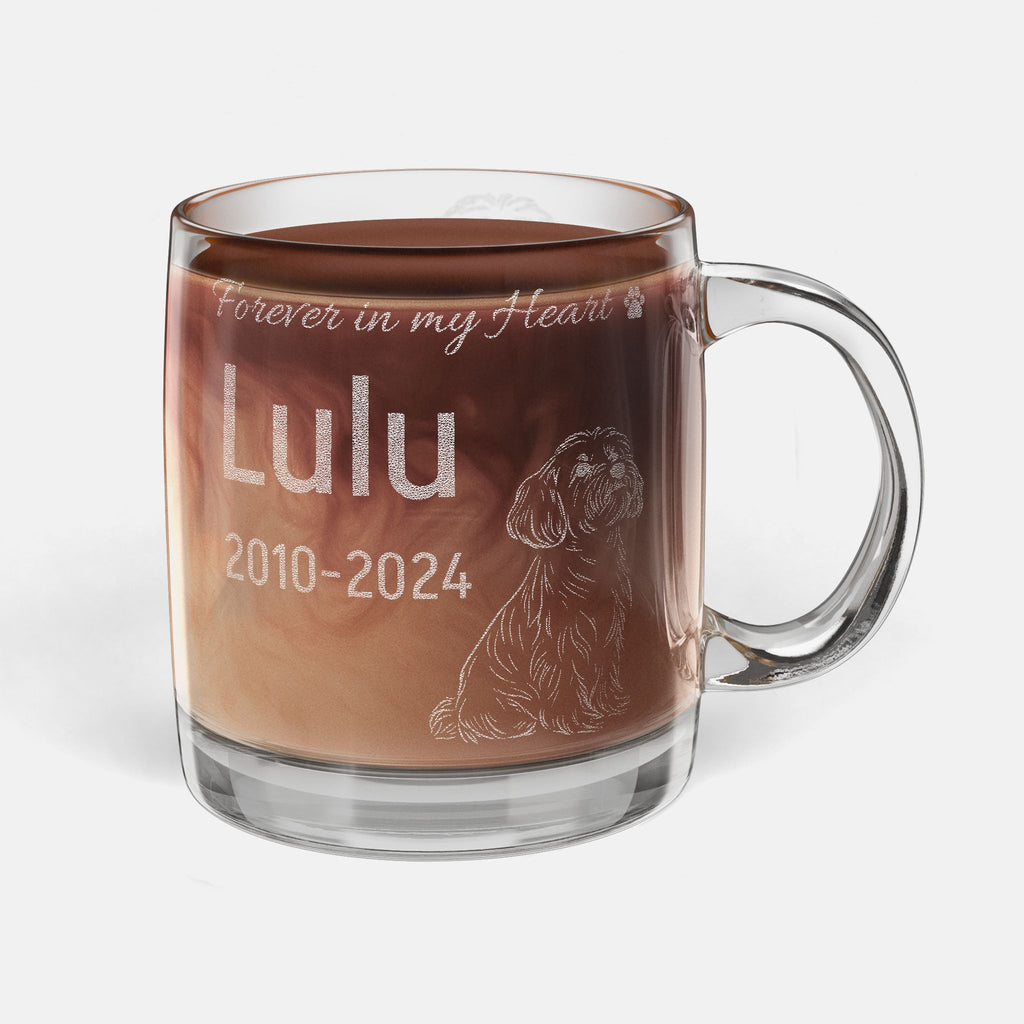 Glass mug with engraved dog illustration and text 'Forever in my Heart Lulu 2010-2024' filled with hot chocolate.