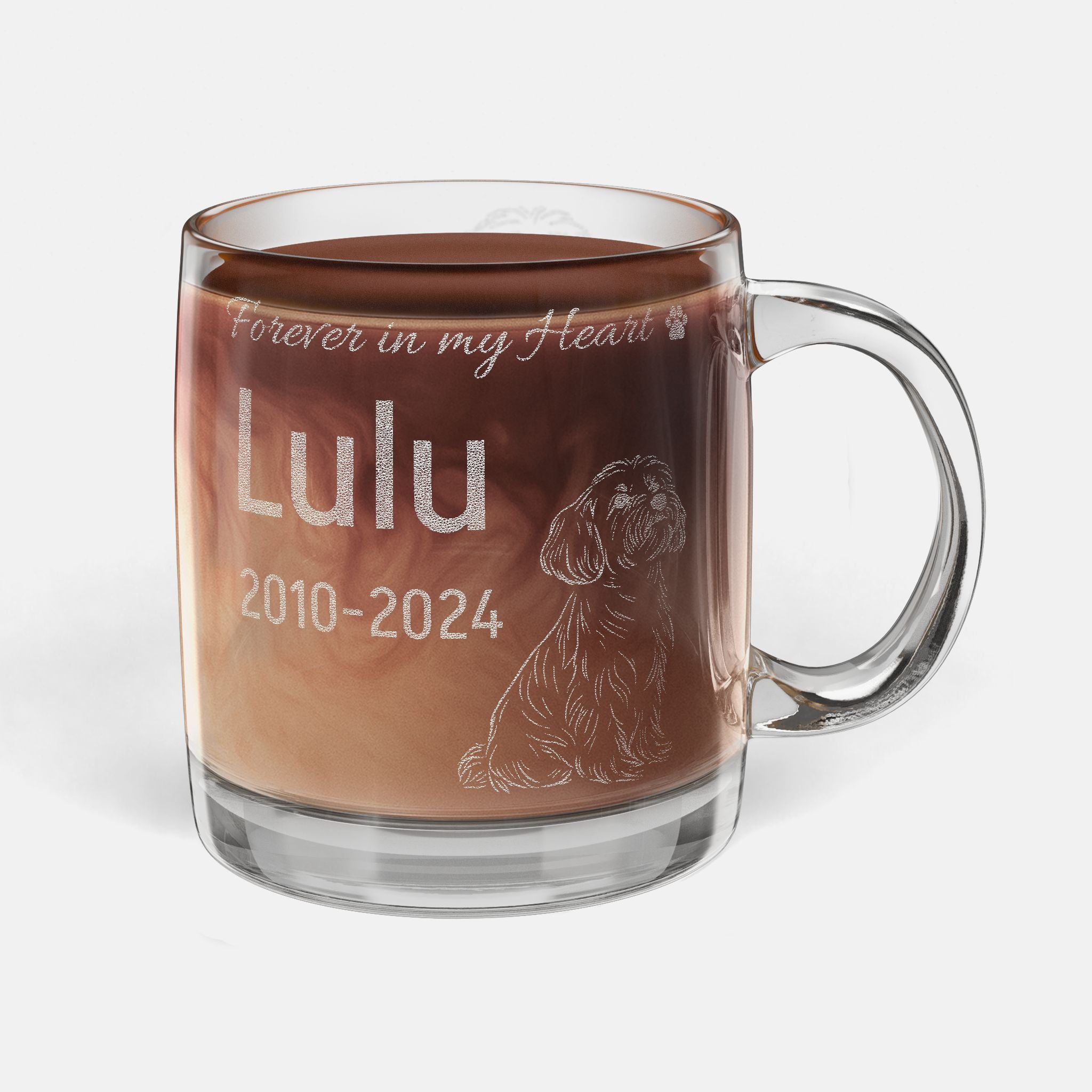 Glass mug with engraved dog illustration and text 'Forever in my Heart Lulu 2010-2024' filled with hot chocolate.