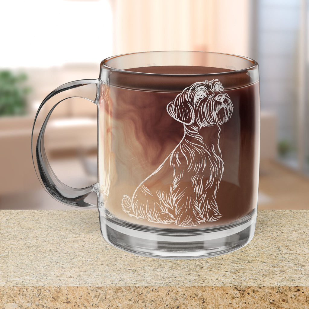 Clear glass mug with a Black Russian Terrier dog engraving filled with hot chocolate on a wooden surface.