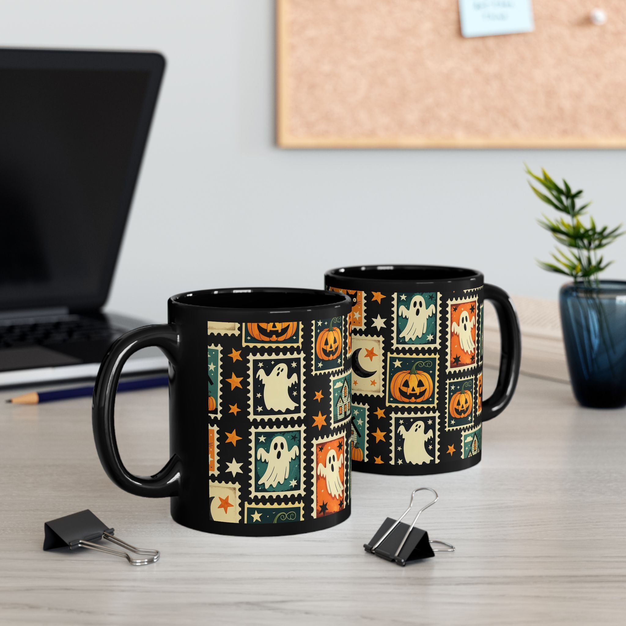 Two Halloween-themed mugs on a desk with a laptop and plant in the background.