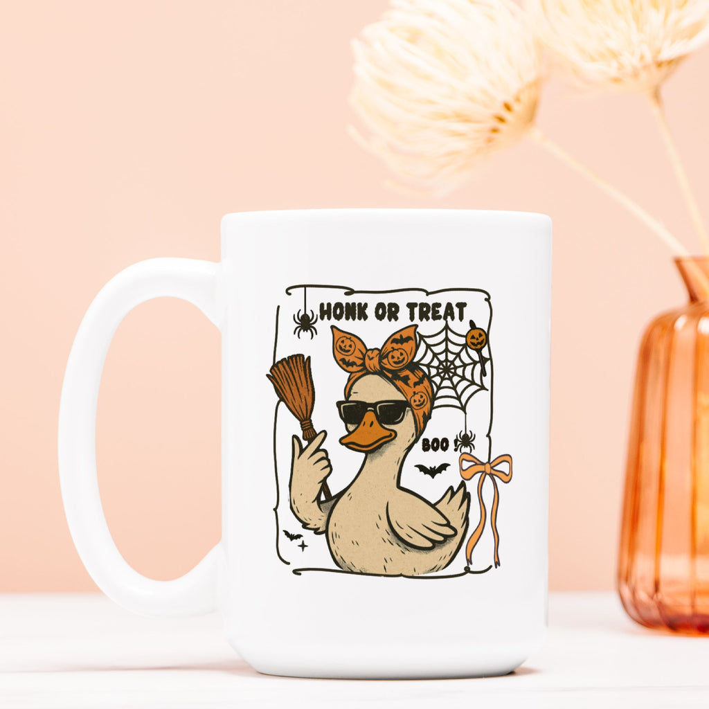 White mug with a Halloween-themed design of a duck, broom, and text on a light pink background.