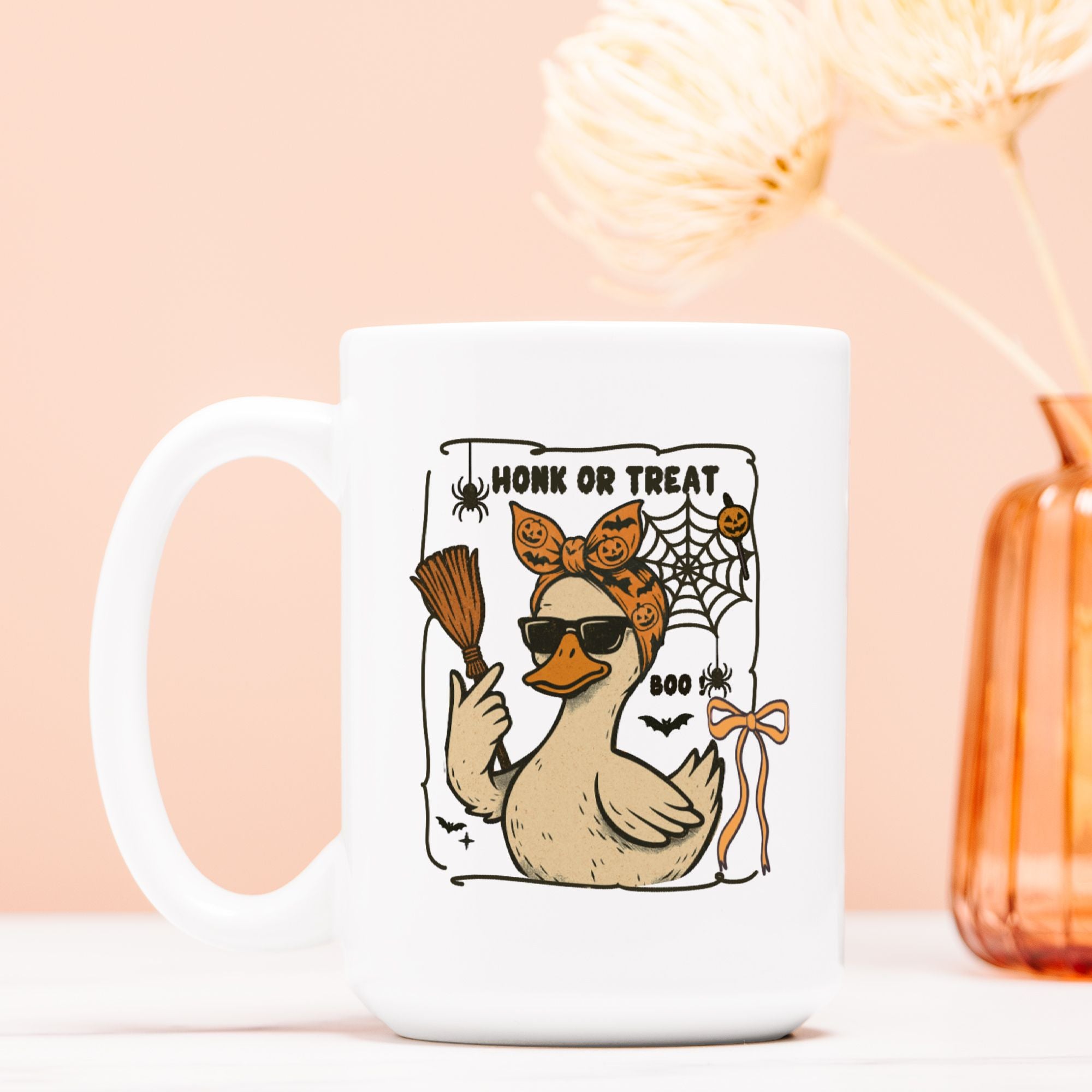 White mug with a Halloween-themed design of a duck, broom, and text on a light pink background.