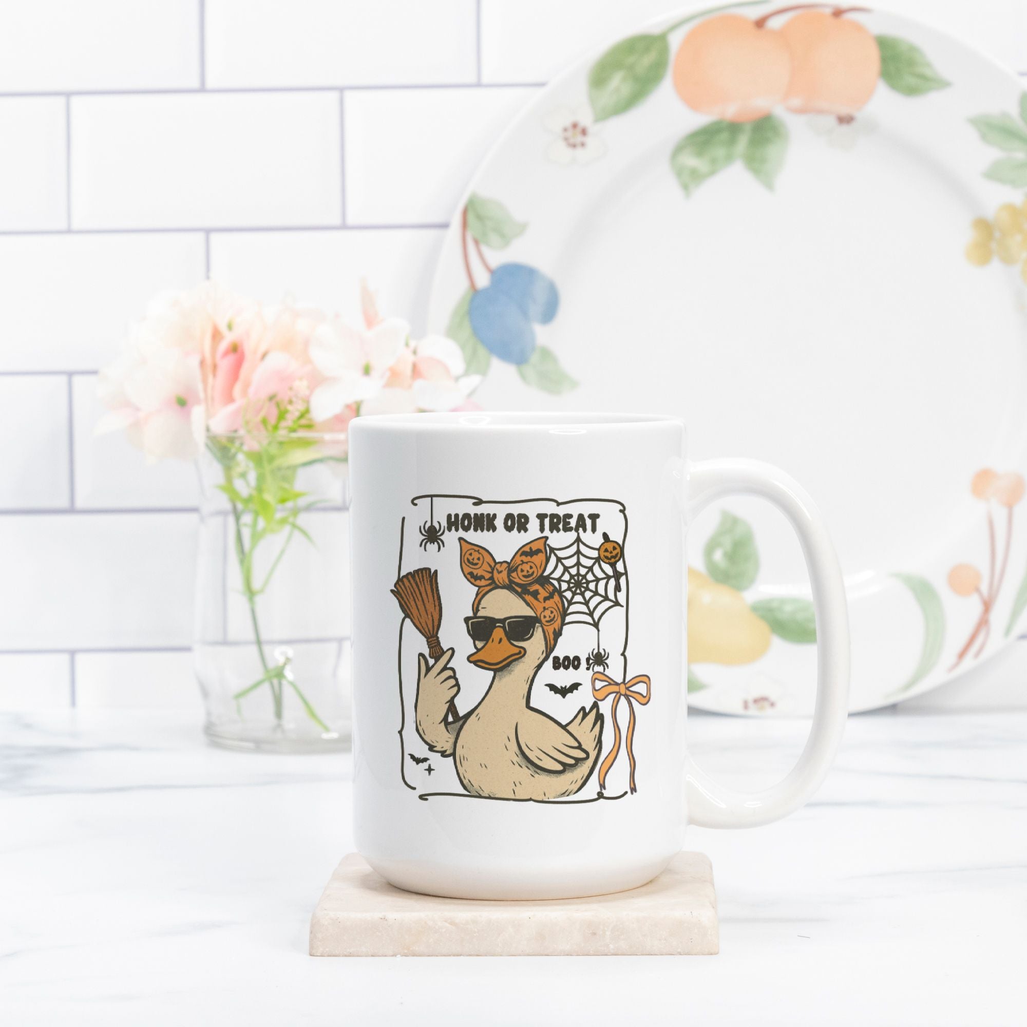 Mug with a duck design and text on a white surface with a decorative plate in the background.