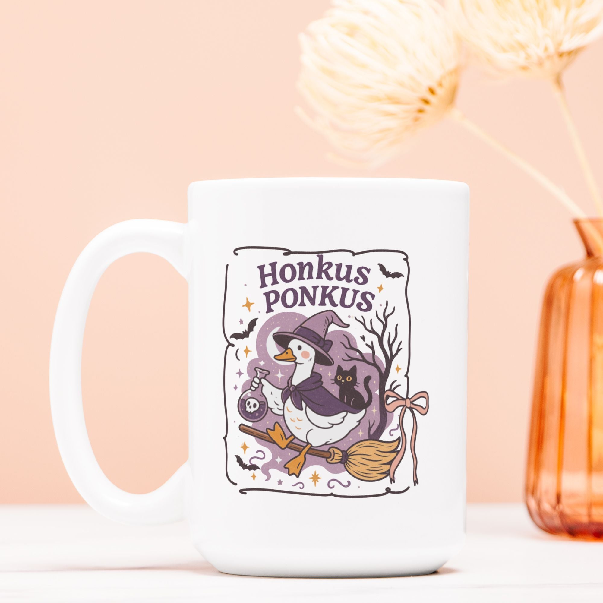 White mug with a Halloween-themed design featuring a duck in a witch hat and broomstick, on a light pink background.