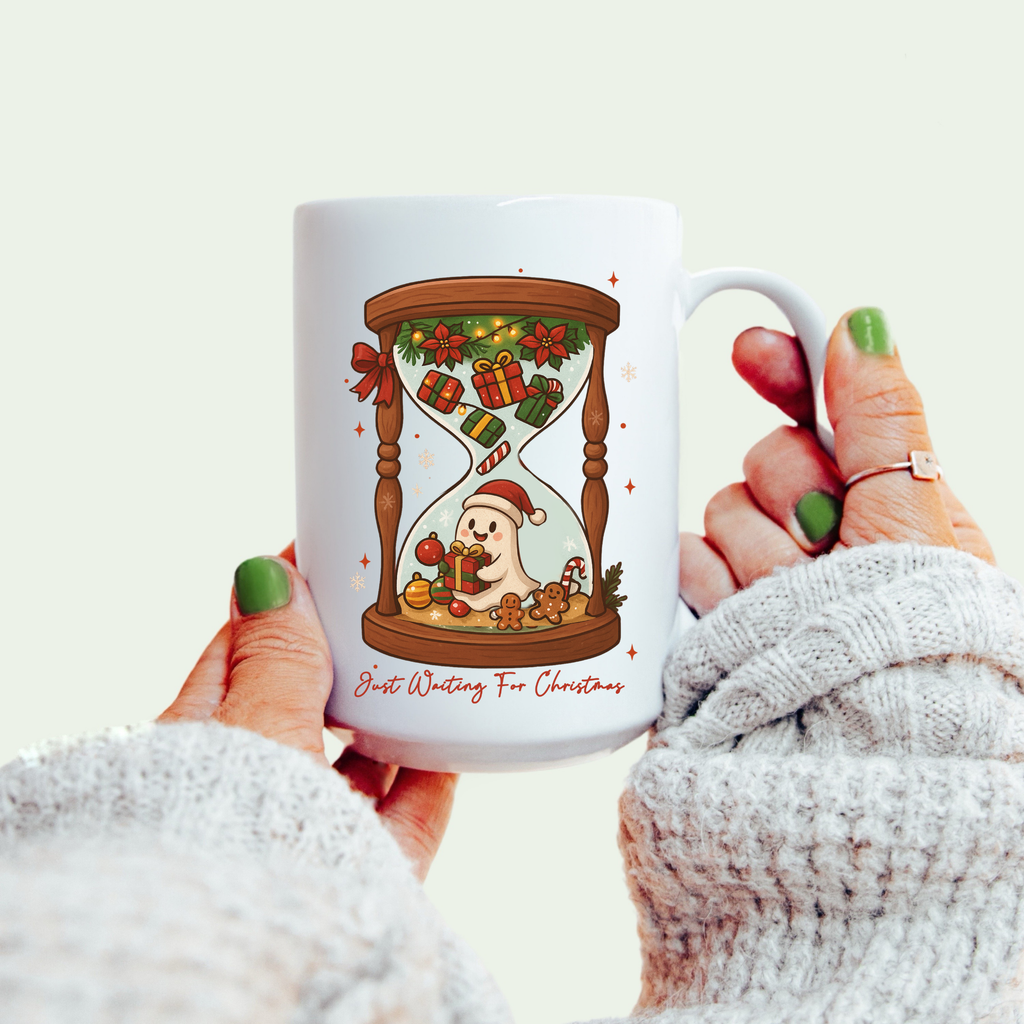White mug with Christmas-themed design held by a person wearing a white sweater.