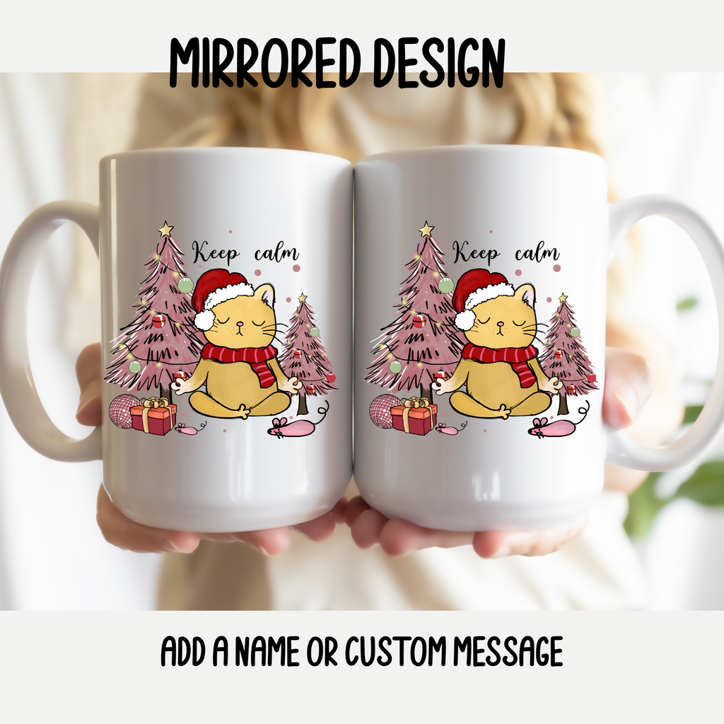 Two mugs with a mirrored design of a cat in a Santa hat and Christmas trees, held together.