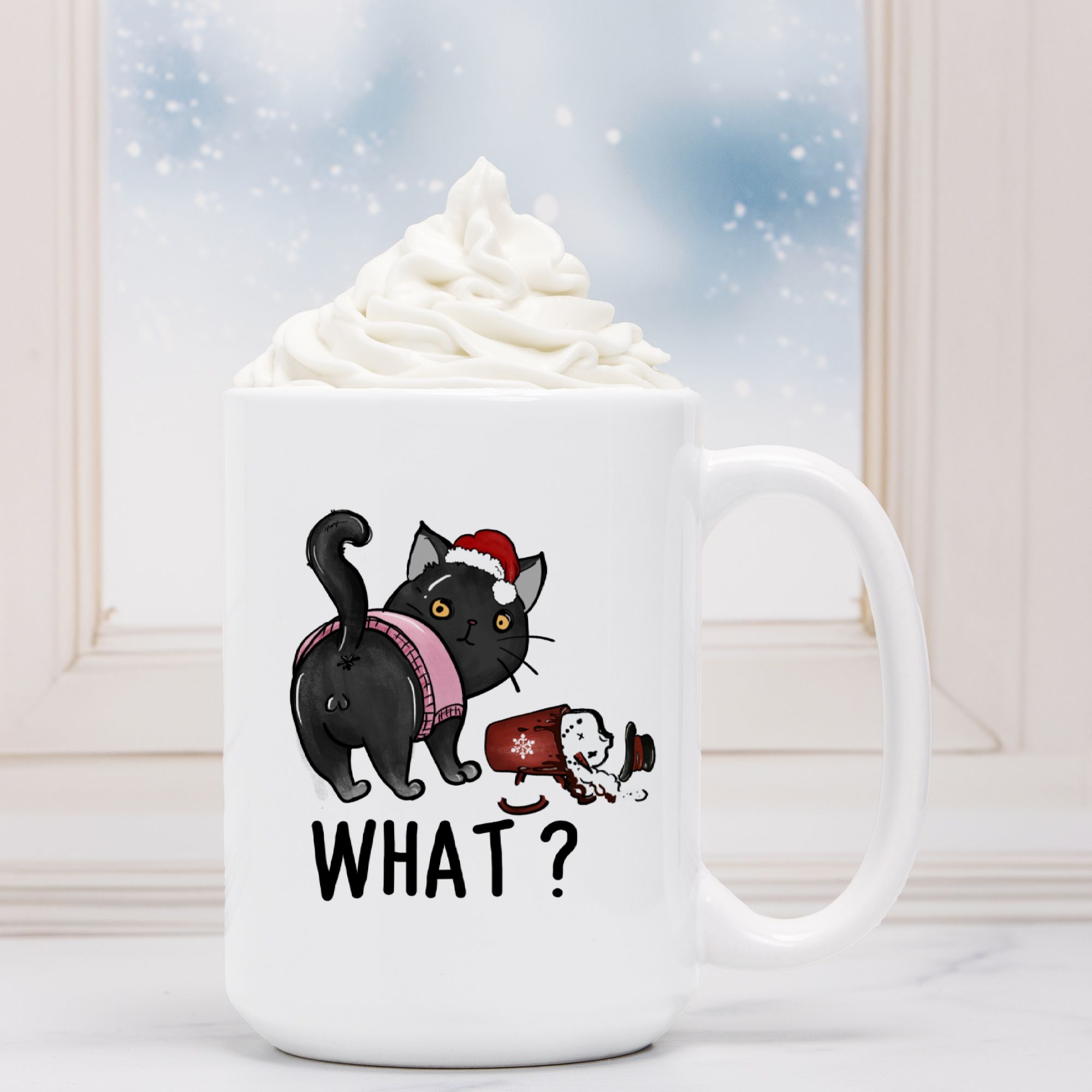 White mug with a black cat Christmas illustration and 'WHAT?' text, filled with hot chocolate.