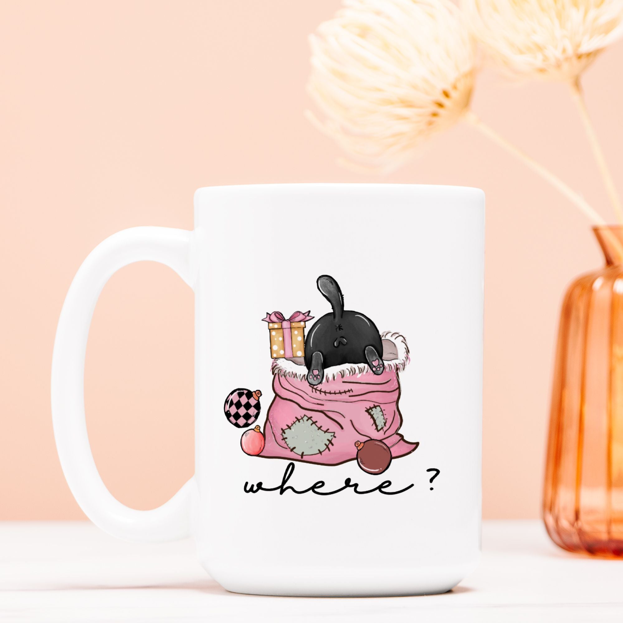 White mug with a cartoon black cat in a pink Christmas bag on a peach background