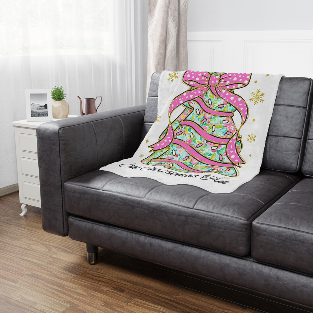 Decorative blanket with a Christmas tree design on a gray sofa in a living room.