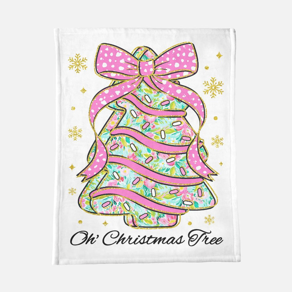 Decorative blanket with a Christmas tree design featuring a pink bow and sprinkles on a white background.