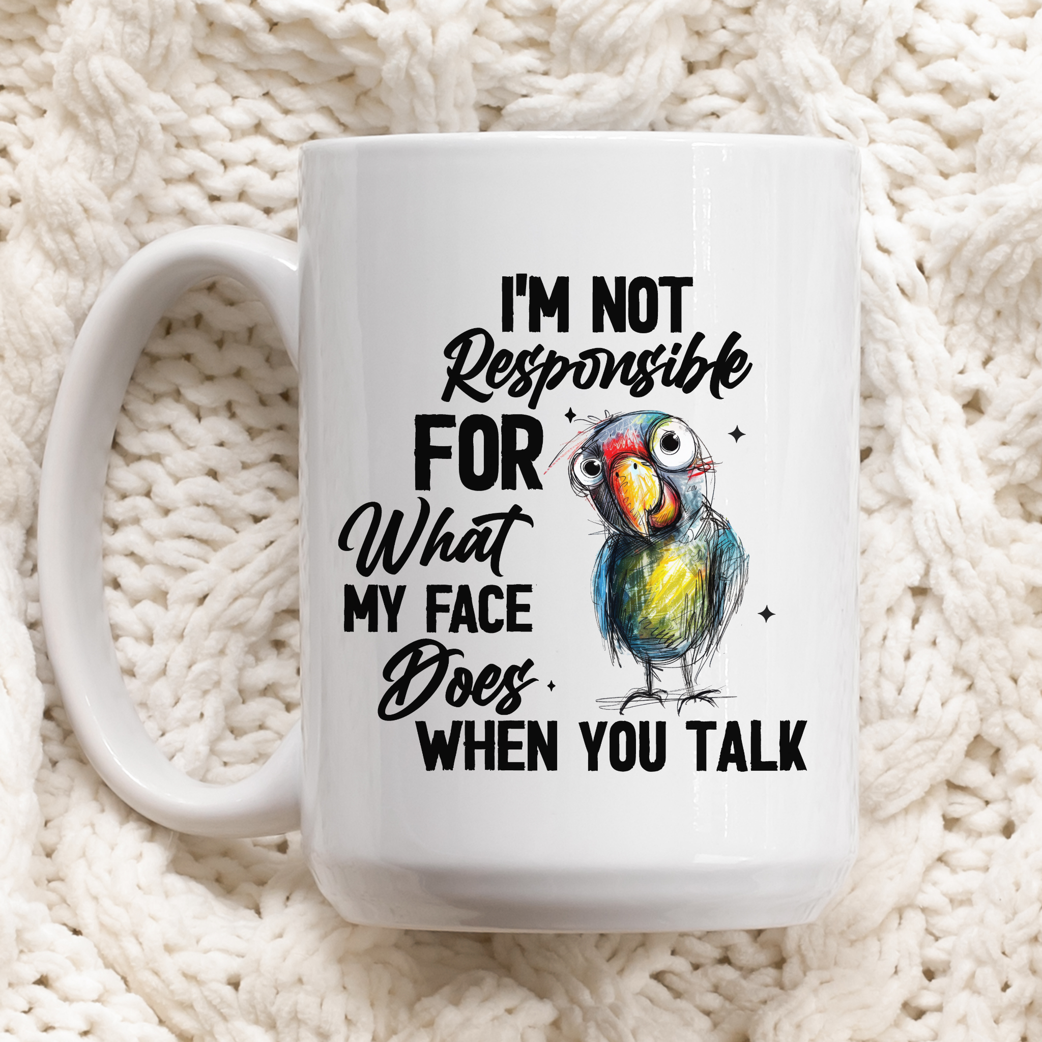 Hand drawn parrot with text ' I'm not responsible for what my face does when you talk' on white mug laying on blanket.