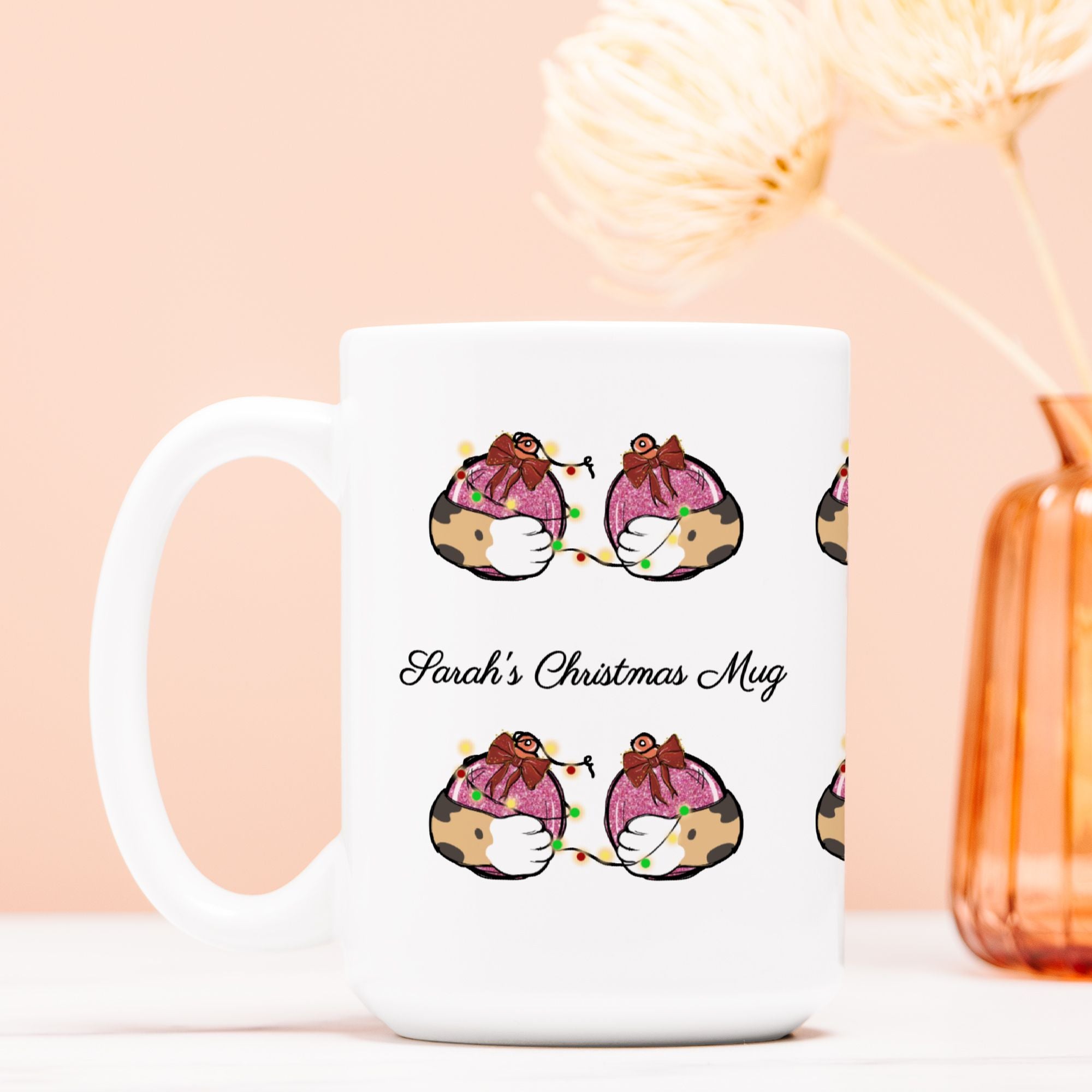 White mug with Christmas-themed design and 'Sarah's Christmas Mug' text on a light pink background