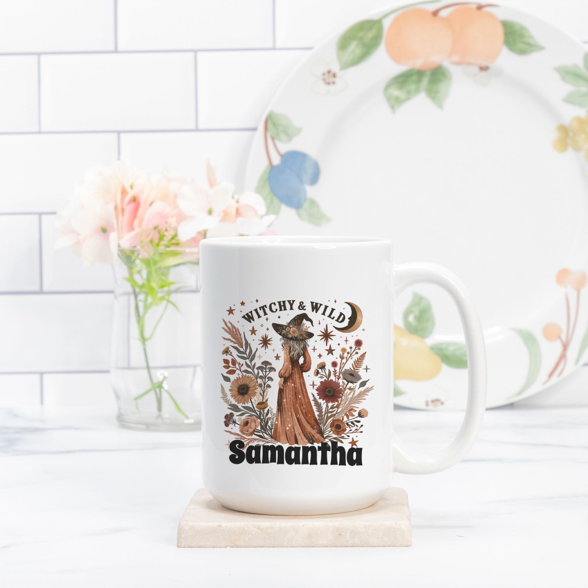 White mug with 'Witchy & Wild Samantha' design on a white surface with a floral plate in the background.