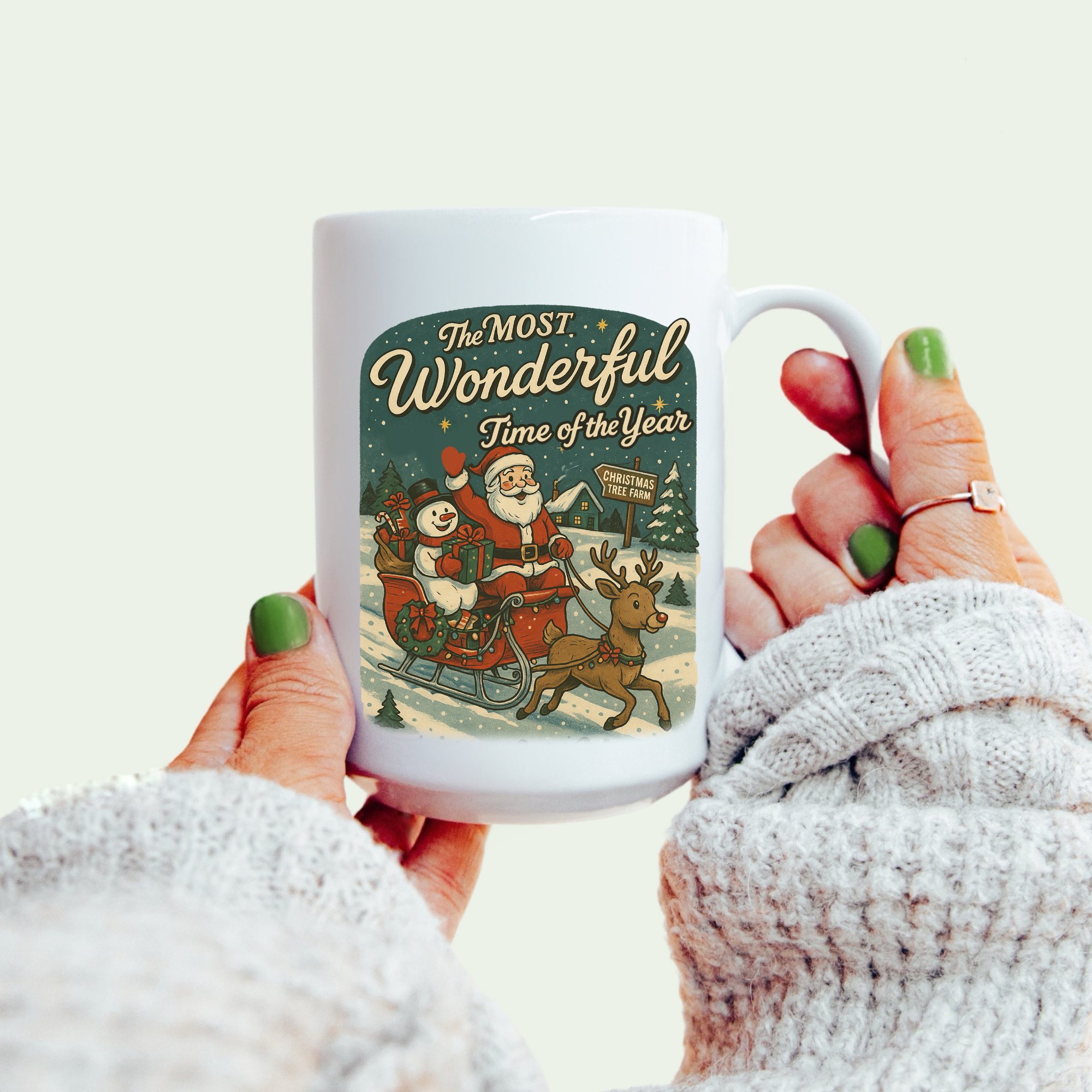 Mug with Christmas design and text held by a person wearing a white sweater.