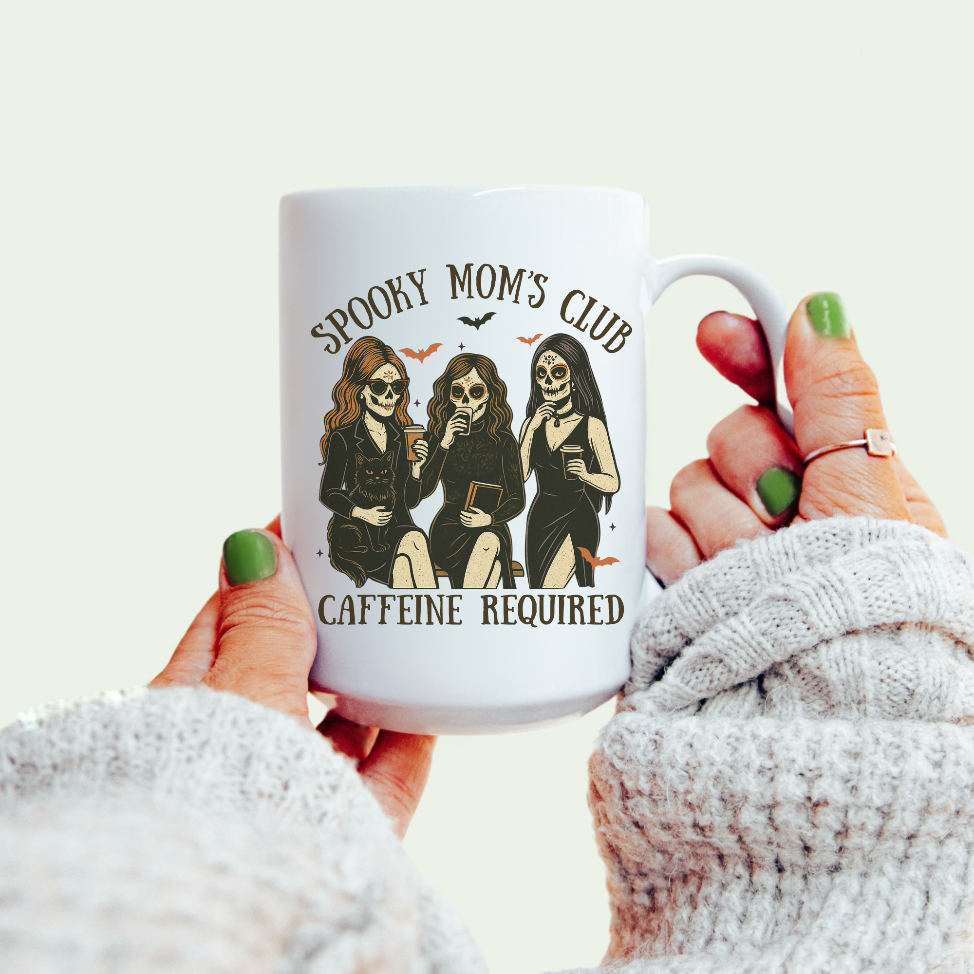 Mug with 'Spooky Mom's Club Caffeine Required' design held by a person wearing a white sweater.