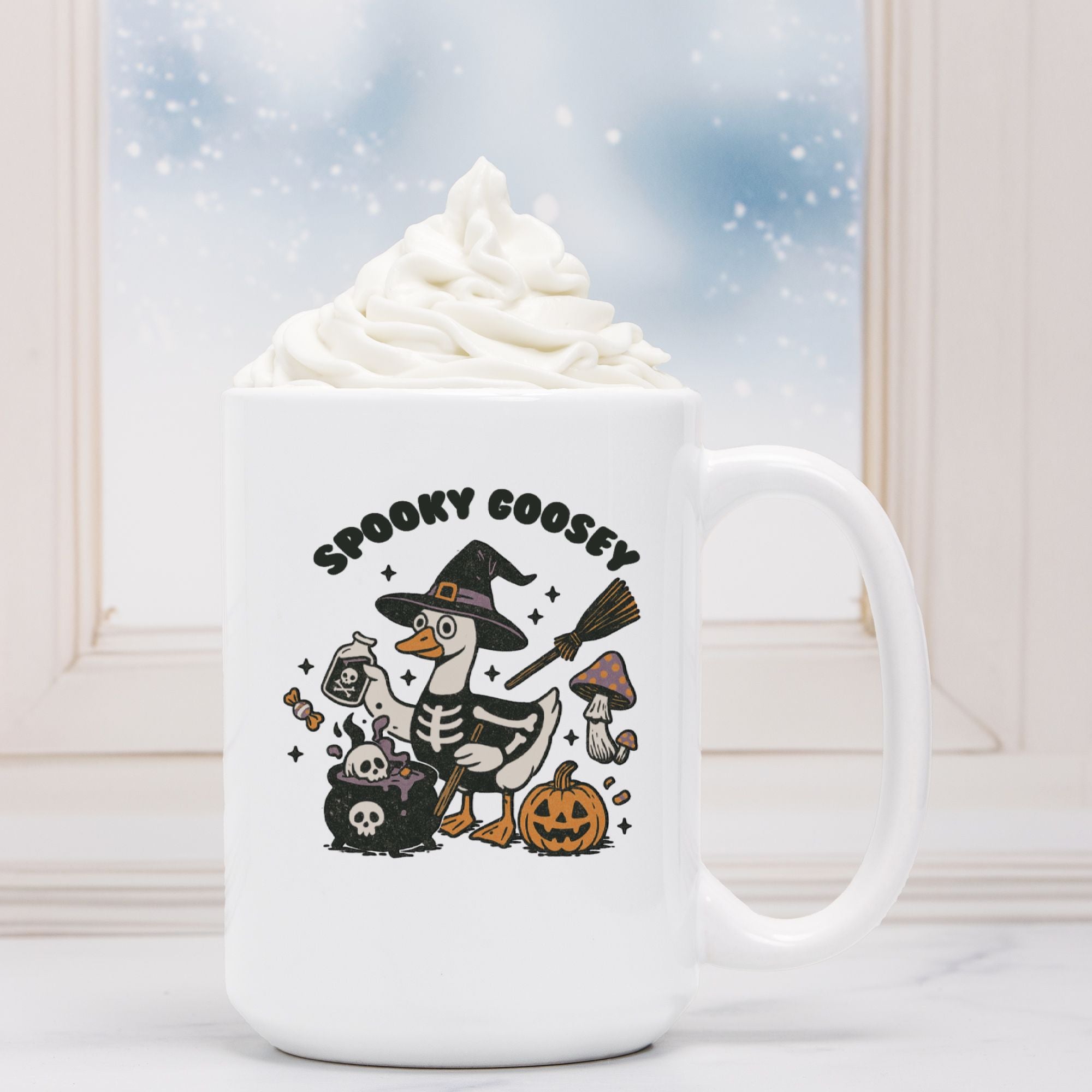 White mug with Halloween-themed design featuring a skeleton goose, broom, and pumpkin, with whipped cream on a snowy background.
