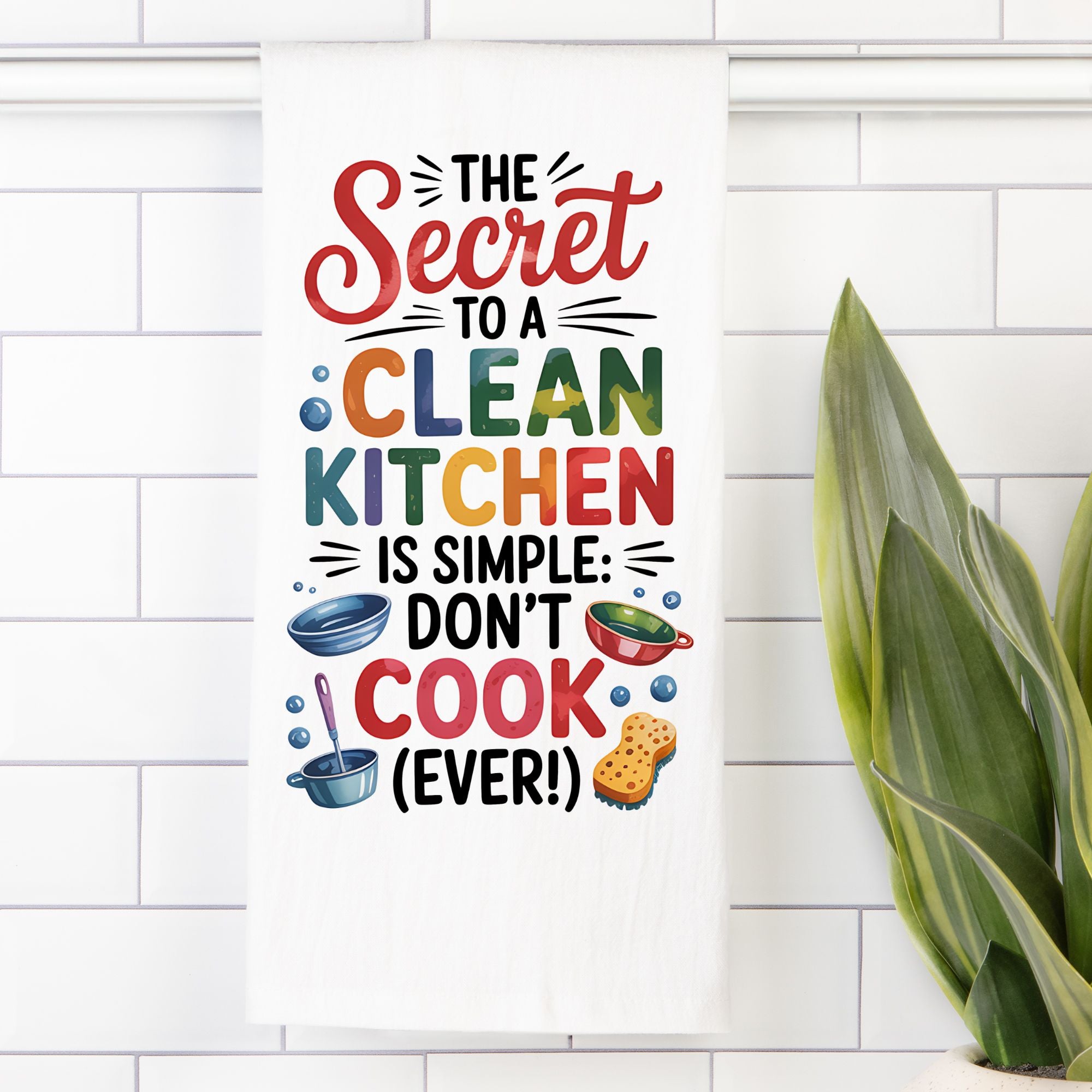 Colorful kitchen towel with humorous quote on a white tiled wall.