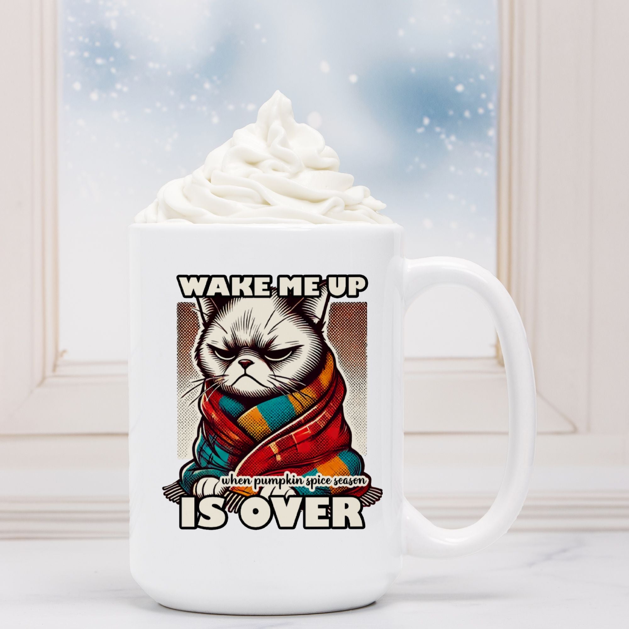 White mug with a graphic of a cat in a scarf and text 'Wake me up when pumpkin spice season is over' against a snowy window background.