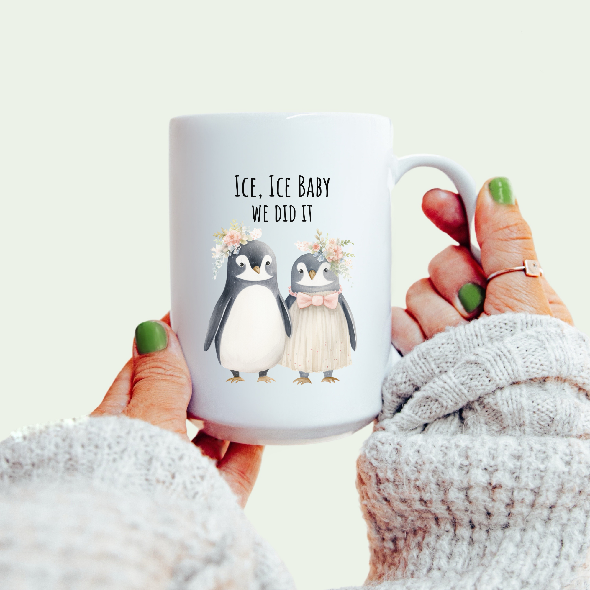 Mug with penguin design and text held by a person wearing a white sweater.