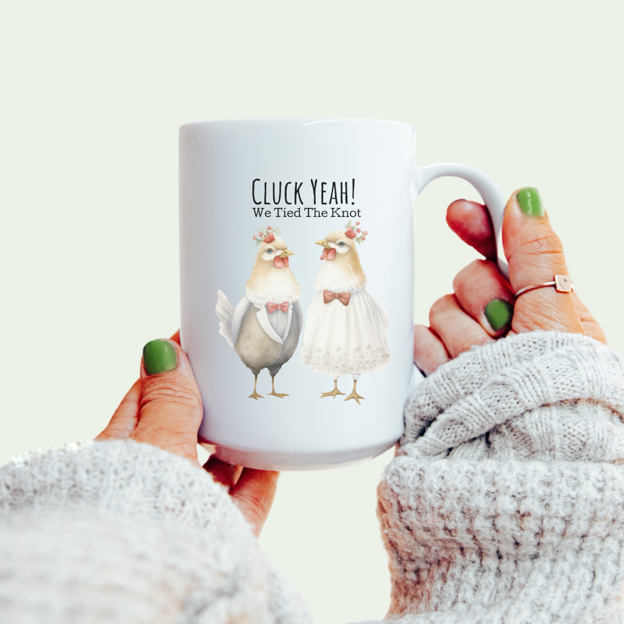 Mug with chicken illustration and text held by a person wearing a white sweater.