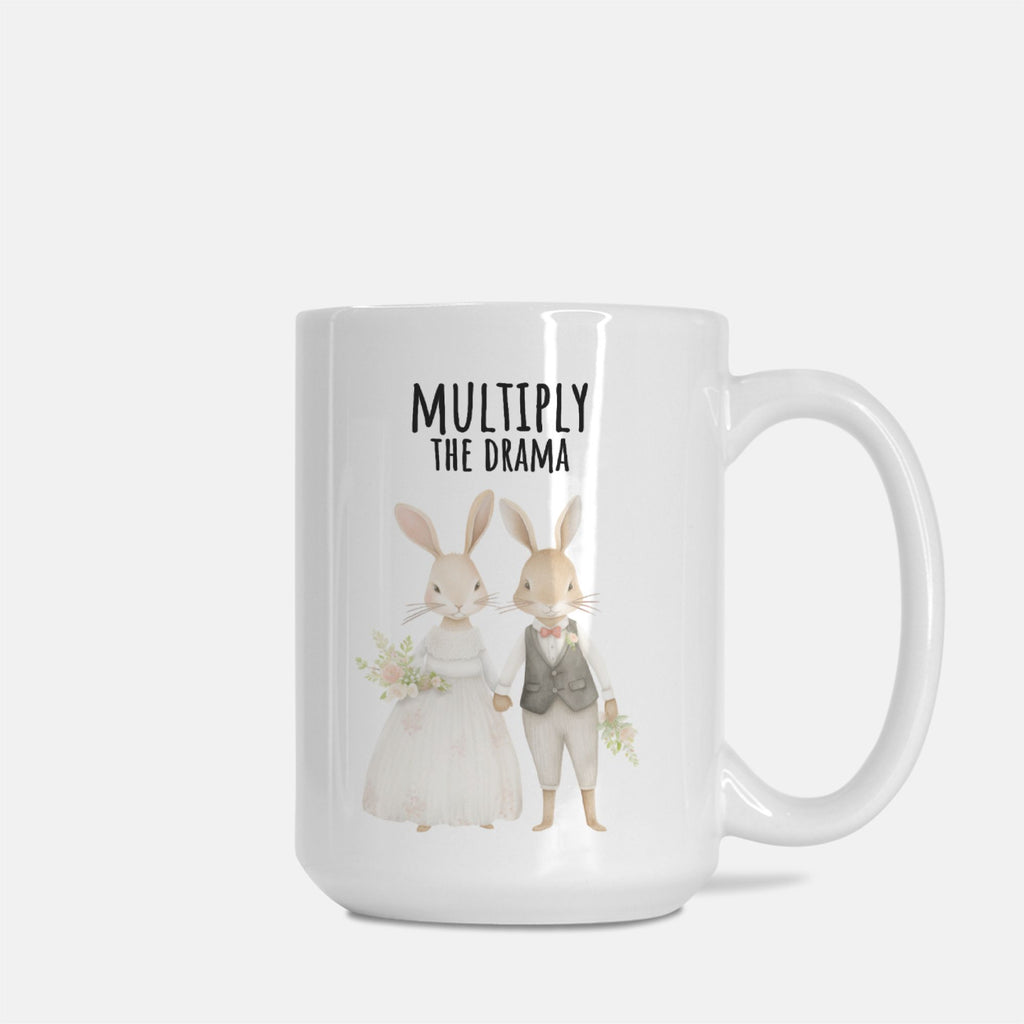 Mug with cartoon bunnies and text 'Multiply The Drama' on a white background
