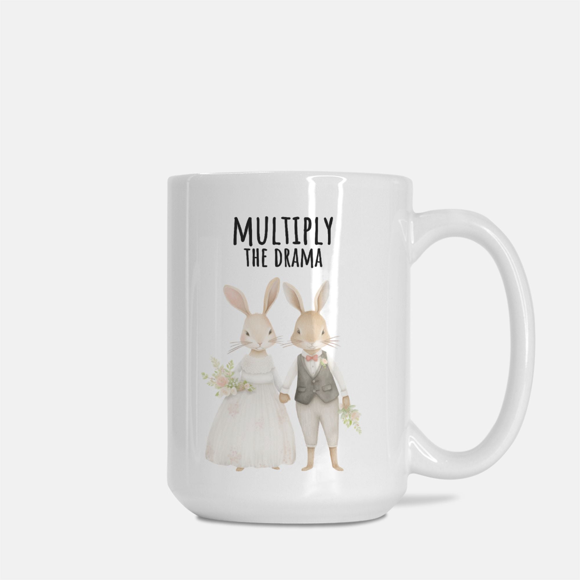 Mug with cartoon bunnies and text 'Multiply The Drama' on a white background