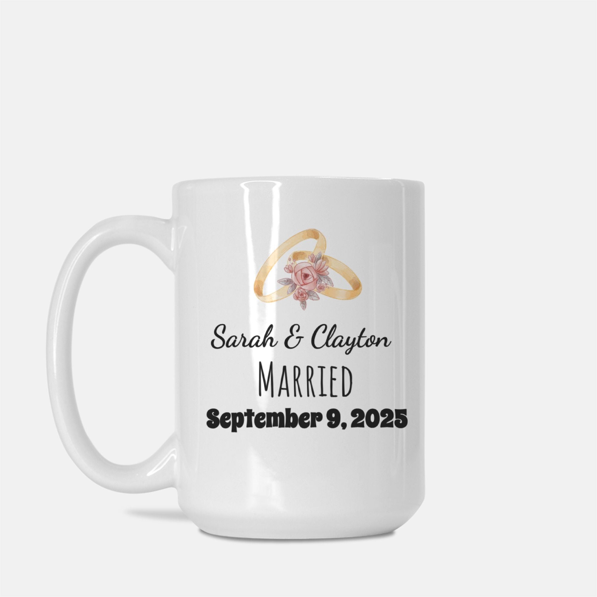 White mug with wedding rings and floral design, personalized with names and date.